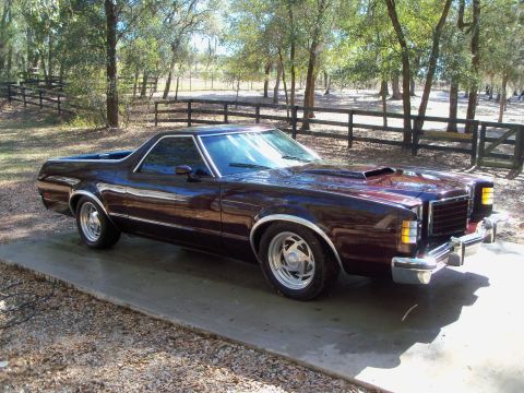 1979 Ford Ranchero - A dark maroon/burgundy 1979 Ford Ranchero car-pickup shown in 3/4 front view, featuring polished five-spot alloy wheels, chrome bumpers, du…