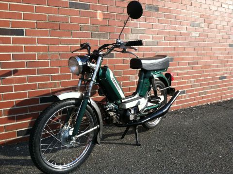 1981 Garelli Rally Sport - A green 1981 Garelli Rally Sport moped is parked in front of a brick wall, showing off its chrome fenders and black exhaust pipe.