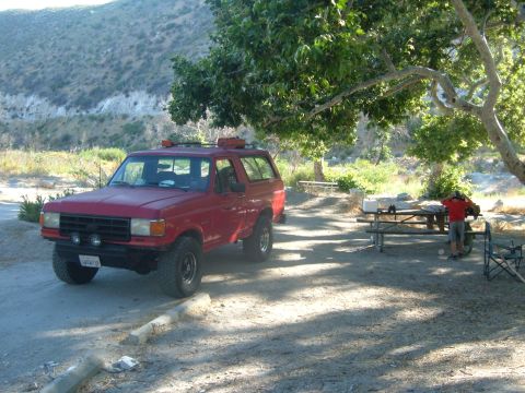 1988 Ford Bronco - This red 1987 Ford Bronco is parked at a campsite, ready for outdoor adventure.