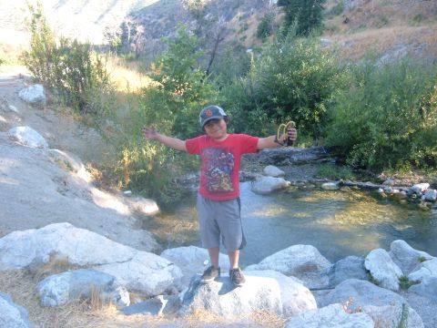 1988 Ford Bronco - A young boy stands with a slingshot in a natural outdoor setting near a body of water.