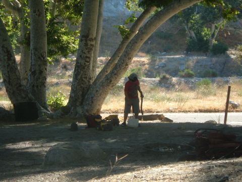1988 Ford Bronco - A person stands with a shovel next to a toy dump truck under large trees in a dry, outdoor setting.