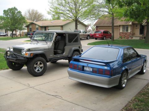 2005 Jeep Wrangler - Two vehicles, a Jeep Wrangler and a Ford Mustang, are parked in a residential driveway.