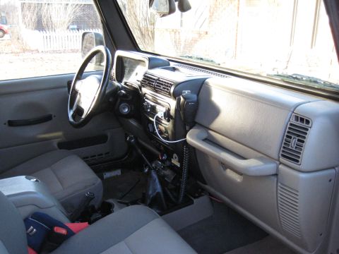 2005 Jeep Wrangler - The interior of a 2005 Jeep Wrangler is captured from the passenger side, revealing the dashboard and seating area.