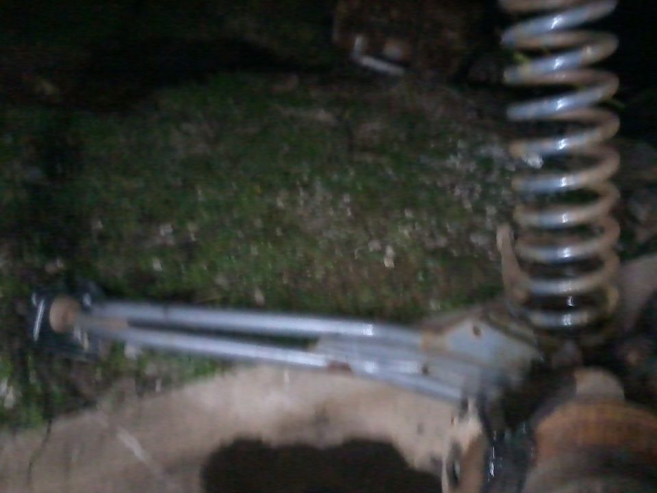 Close-up of a vehicle's coil spring and suspension arm, possibly for sale