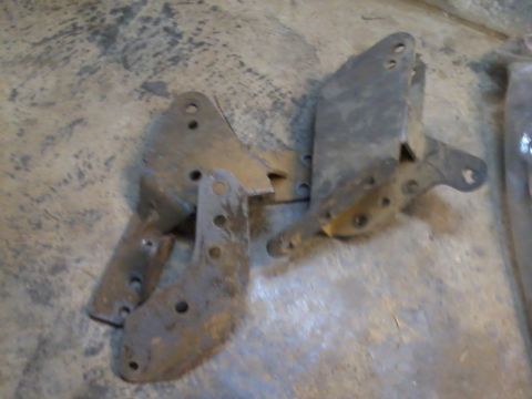1995 Ford Bronco - Collection of metal brackets, likely for automotive use, shown on a concrete surface.