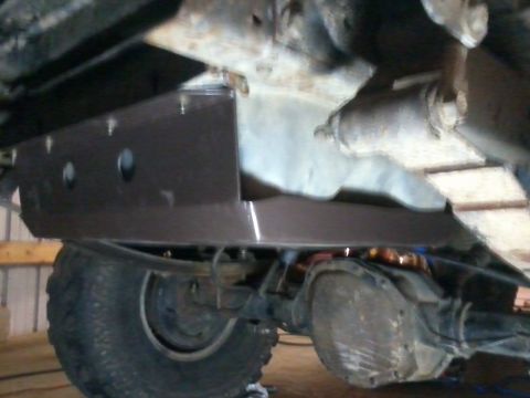 1995 Ford Bronco - Close-up view of a vehicle's undercarriage, focusing on a skid plate and rear axle assembly.