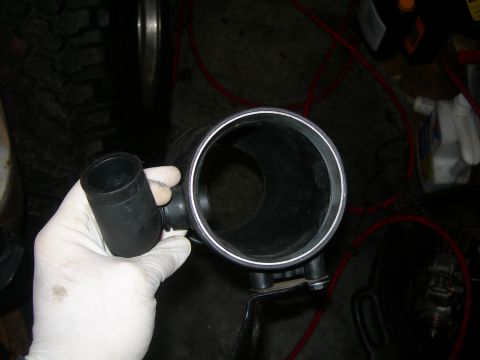 1984 Ford Bronco - A gloved hand holds a black intake tube with a smaller hose attached, likely for a supercharger installation.