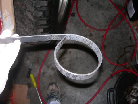 1984 Ford Bronco - A metal band is being bent, with a tire and red cables visible in the background.