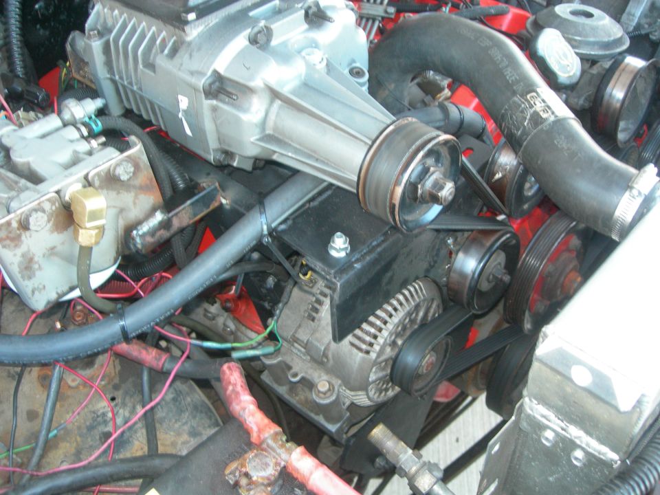 Engine bay with a silver supercharger, black hoses, and red wiring