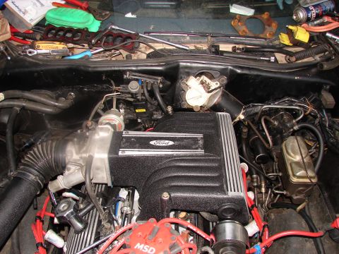 1973 Ford Ranchero - A cluttered engine bay with a Ford intake manifold and MSD ignition components is visible, along with scattered tools.