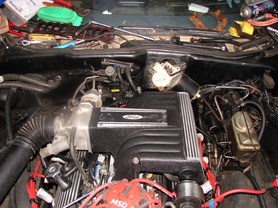 Engine bay with Ford branding on the intake manifold, MSD ignition, and various tools scattered around