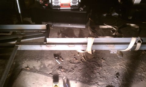 1990 Ford Bronco - Metal frame construction is underway in a workshop, with straps holding pieces together.