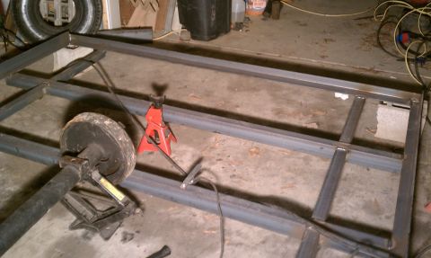 1990 Ford Bronco - A metal frame is under construction, supported by a jack stand, with an axle and tire visible.