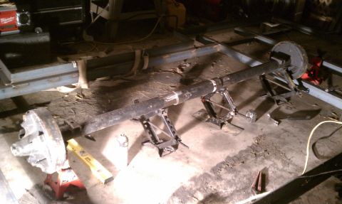 1990 Ford Bronco - A trailer axle assembly is shown supported by jack stands in a workshop setting.