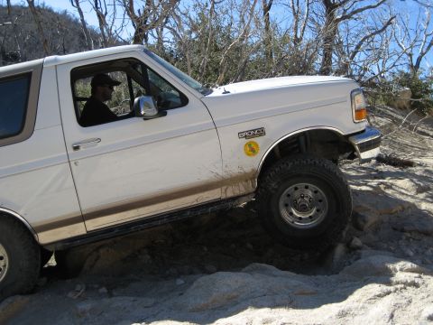 1996 Ford Bronco - A white 1996 Ford Bronco navigates a challenging off-road course, demonstrating its capabilities.