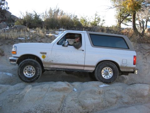1996 Ford Bronco - A man drives a white 1996 Ford Bronco over a rocky trail.