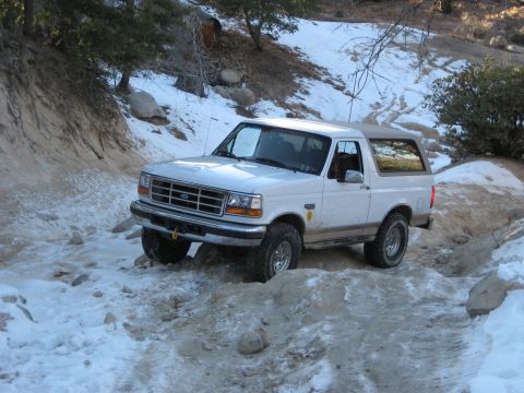 1996 Ford Bronco - A white 1996 Ford Bronco navigates a challenging snowy and rocky path.