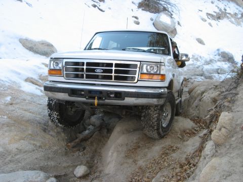 1996 Ford Bronco - 1996 Ford Bronco tackling a challenging rocky trail in a snowy environment.