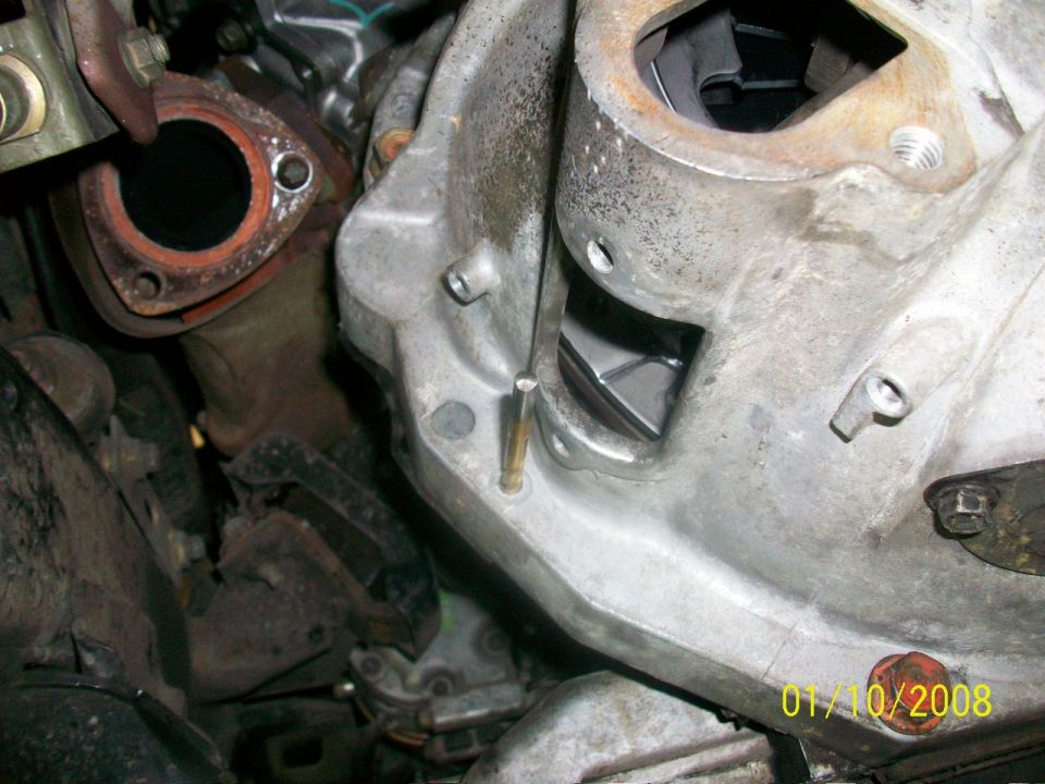 Close-up of engine block and exhaust manifold connection, showing metal components and bolts
