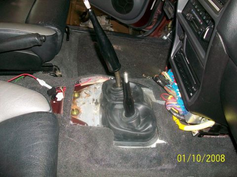 2000 Isuzu Vehicross - The interior of a vehicle shows exposed mechanical components and wiring beneath the floor mats and center console.