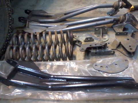 1995 Ford Bronco - A collection of vehicle suspension parts, including springs and control arms, are displayed on a floor.