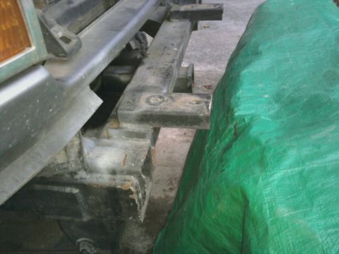 1995 Ford Bronco - This photo shows a section of a vehicle's frame and bumper, with a green tarp obscuring part of the view.