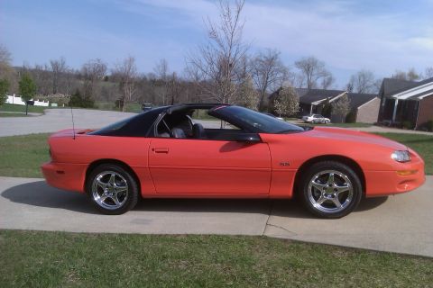 1999 Chevrolet Camaro - Side view of an orange 1999 Chevrolet Camaro SS with a black T-top roof.