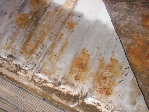 1993 Ford Bronco - The interior floor shows significant rust and corrosion, with a section of carpet rolled back.