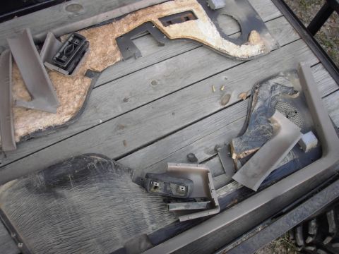 1993 Ford Bronco - Several disassembled car door panels and interior trim pieces are laid out on a wooden surface.