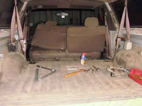 1993 Ford Bronco - The interior of a vehicle shows removed seats and various tools scattered on the floor, suggesting maintenance or modification.