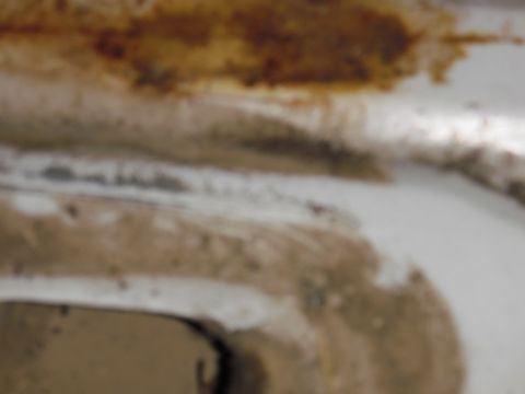 1993 Ford Bronco - The image shows a close-up view of rust and dirt accumulation on a white surface, possibly part of a vehicle's undercarriage or body panel.