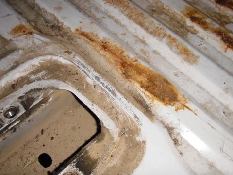 1993 Ford Bronco - Close-up of a worn truck bed liner with visible rust and dirt accumulation.