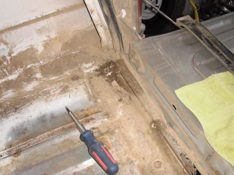 1993 Ford Bronco - The interior of a truck bed shows dirt and grime, with a screwdriver and a yellow rag present.