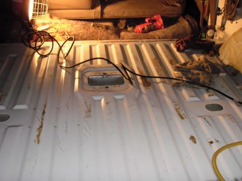 1993 Ford Bronco - Interior of a white truck bed, showing the ribbed metal floor, a work light, and a power tool.
