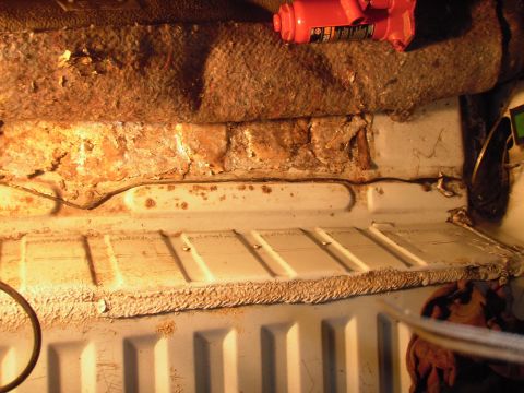 1993 Ford Bronco - Interior floor pan shows significant rust and damage, with a jack visible.
