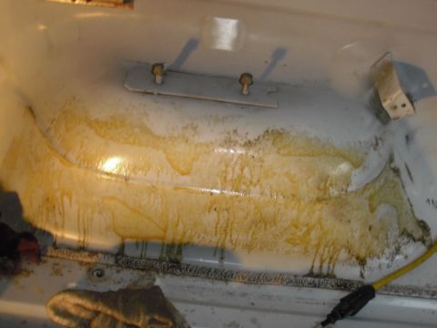 1993 Ford Bronco - The interior of a vehicle bedliner shows significant staining and wear, with a metal plate secured by bolts.