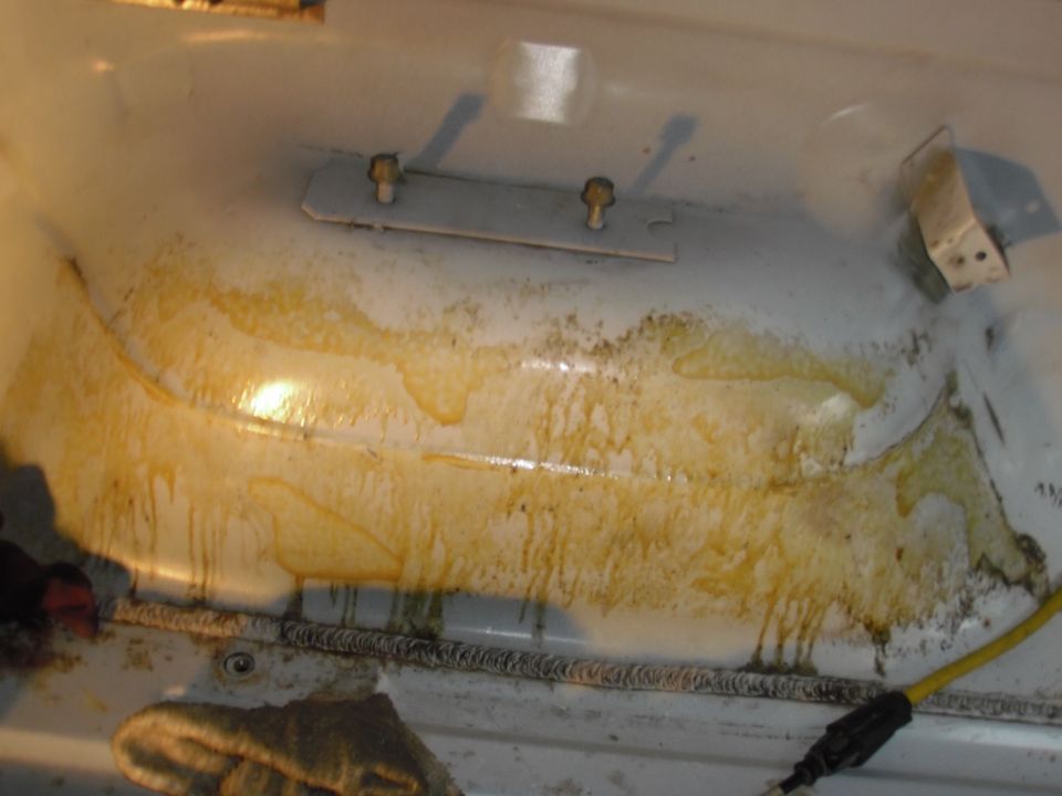 close-up of a dirty vehicle bedliner with yellow stains and two bolts holding a metal plate