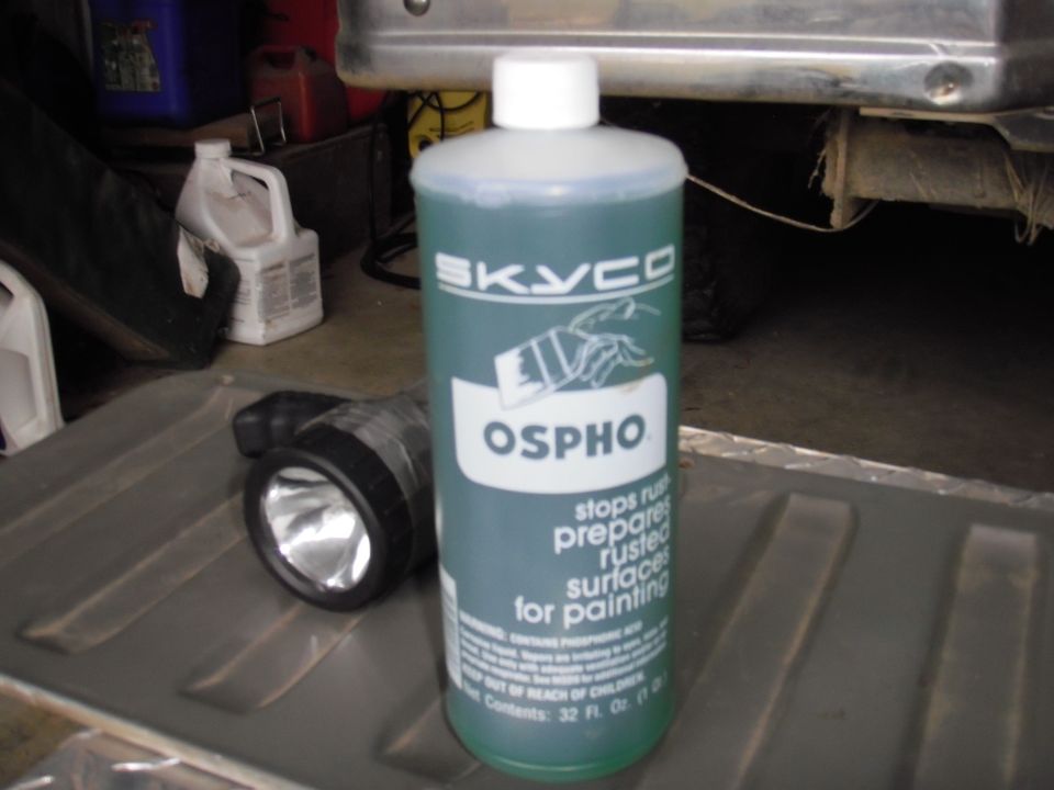 Bottle of Skyco Ospho rust treatment and a flashlight on a textured surface