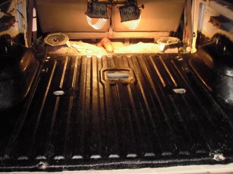 1993 Ford Bronco - The cargo area of a vehicle is shown with a freshly applied black bedliner and work lights.