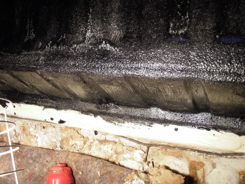 1993 Ford Bronco - Close-up view of a vehicle's underbody, showing rust and a black bedliner coating. The Supermotors.net logo is visible in the corner.