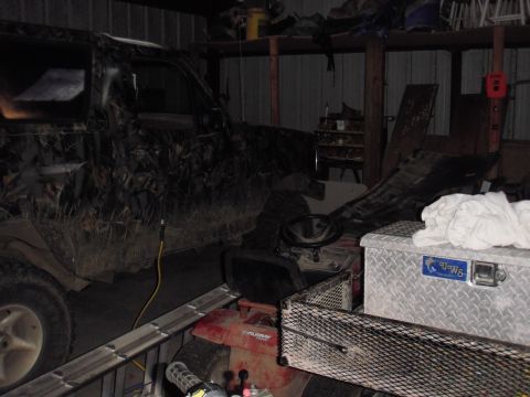 1993 Ford Bronco - A camouflaged SUV is parked inside a garage next to a riding mower and a metal toolbox.