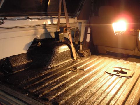 1993 Ford Bronco - The interior of a vehicle shows a bedliner with a seatbelt and a bright light illuminating the area.
