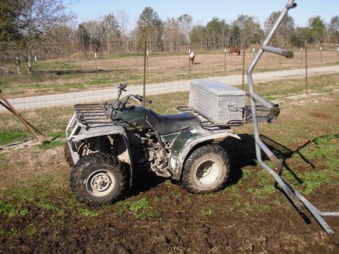 1993 Ford Bronco - An all-terrain vehicle sits in a grassy area with a fence and trees in the background.