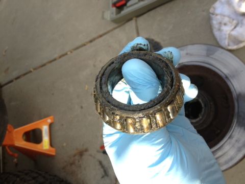 1979 Ford Bronco - A heavily used wheel bearing is held up for inspection, showing signs of significant wear and grease contamination.