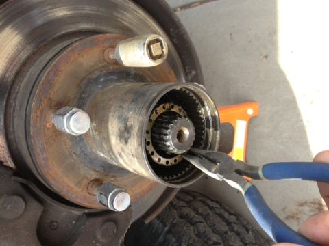 1979 Ford Bronco - Close-up of a vehicle's front wheel hub assembly with pliers being used.