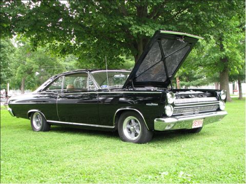 1966 Mercury Comet - A black 1966 Mercury Comet coupe sits on a grassy area with its hood open, revealing the engine bay.