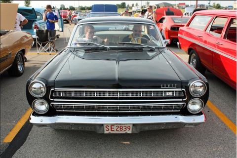 1966 Mercury Comet - A black 1966 Mercury Comet is parked at an outdoor event, with other vehicles visible.
