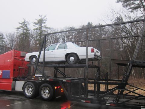 1991 Ford Crown Victoria LTD - A white 1991 Ford Crown Victoria LTD is being transported on a car carrier.