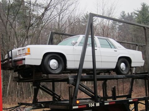 1991 Ford Crown Victoria LTD - Side view of a white 1991 Ford Crown Victoria LTD being transported on a car carrier.