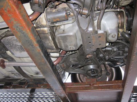 1991 Ford LTD Crown Victoria - The underside of a vehicle reveals its mechanical components and shows signs of rust on the frame and chassis.